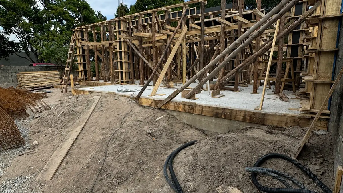 Obra em fase de fundação com fôrmas de madeira e ferragens estruturais para concretagem