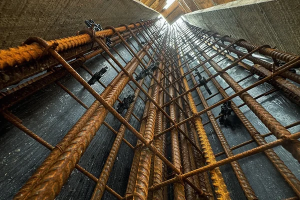 Vista de baixo para cima de armação de ferragens amarradas em pilar de concreto
