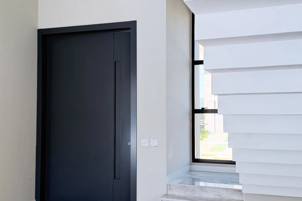Interior de residência finalizada com porta de entrada preta e escada com degraus em ripas brancas